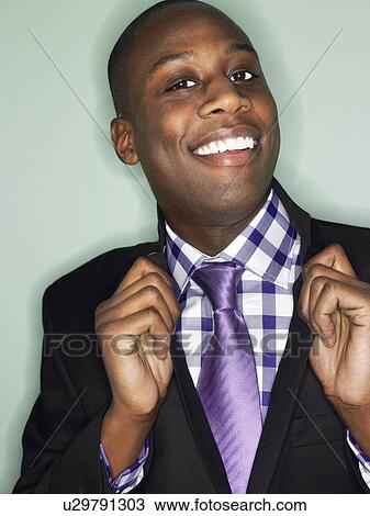 Stock Image - Businessman holding lapels in studio head and shoulders. Fotosearch
