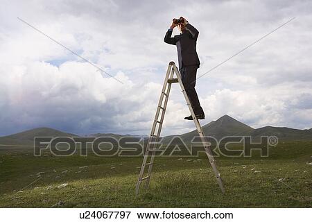 Businessman in mountain field on ladder Looking Through Binoculars low angle view View Large Photo Image Stock Photo - Businessman in mountain field on ladder Looking Through Binoculars low angle view. Fotosearch