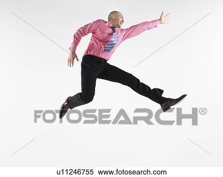Businessman jumping in studio side view View Large Photo Image Stock Photography - Businessman jumping in studio side view. Fotosearch