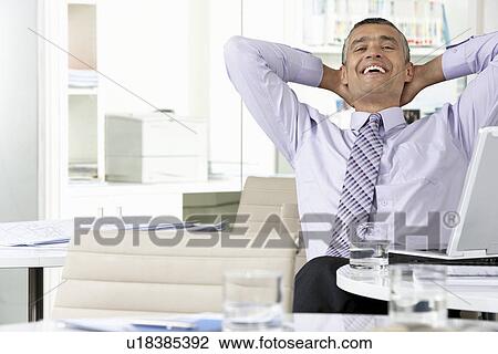 Businessman leaning back at office desk View Large Photo Image Stock Image - Businessman leaning back at office desk. Fotosearch