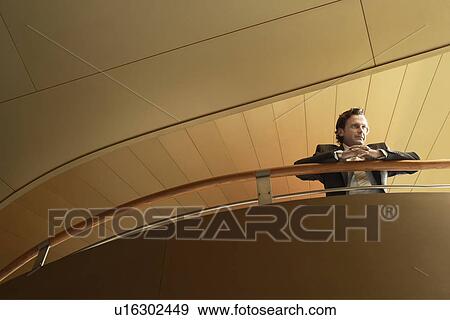 Stock Photo - Businessman leaning on railing low angle view.. Fotosearch