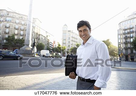 Businessman on city street holding briefcase View Large Photo Image Stock Photograph - Businessman on city street holding briefcase. Fotosearch