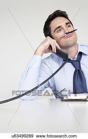 Businessman on phone balancing pen on upper lip View Large Photo Image Stock Photo - Businessman on phone balancing pen on upper lip. Fotosearch