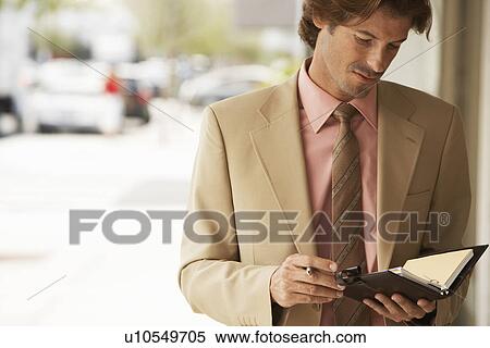 Businessman reading diary in street close-up View Large Photo Image Stock Photography - Businessman reading diary in street close-up. Fotosearch