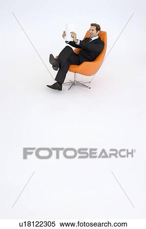 Stock Photography - Businessman reading in chair on white background. Fotosearch
