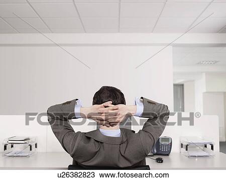 Businessman relaxing at desk in office View Large Photo Image Stock Image - Businessman relaxing at desk in office. Fotosearch