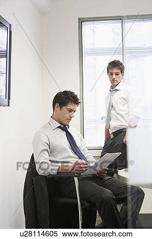 Stock Photography - Businessman reviewing files of other businessman. Fotosearch
