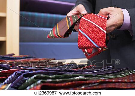 Businessman selecting ties in clothes store mid section View Large Photo Image Stock Photo - Businessman selecting ties in clothes store mid section. Fotosearch