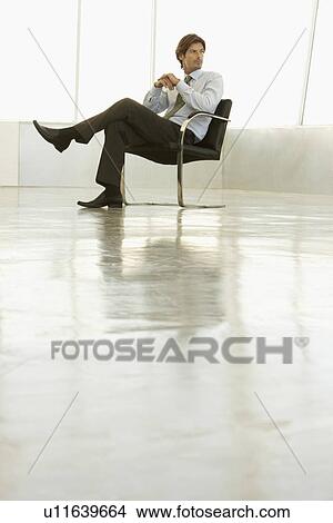 Businessman sitting in empty conference room View Large Photo Image Picture - Businessman sitting in empty conference room. Fotosearch