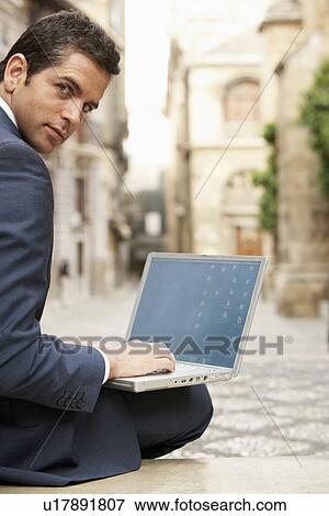 Businessman sitting on bench in street using laptop back view portrait. View Large Photo Image Stock Photo - Businessman sitting on bench in street using laptop back view portrait.. Fotosearch