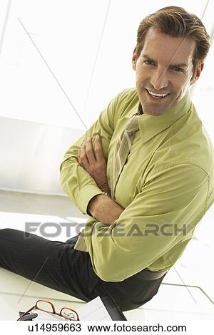 Stock Image - Businessman Sitting on Desk. Fotosearch