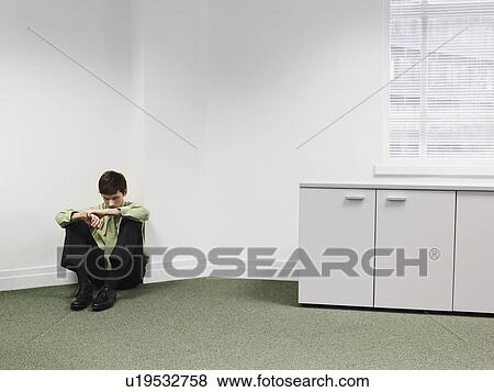 Stock Photo - Businessman sitting on floor in corner of office. Fotosearch