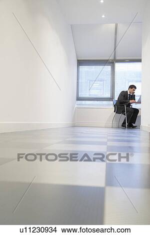 Businessman sitting Using Laptop in empty room ground view View Large Photo Image Picture - Businessman sitting Using Laptop in empty room ground view. Fotosearch