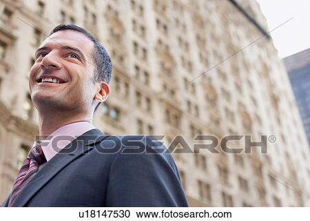 Stock Image - Businessman smiling outdoors low angle view. Fotosearch