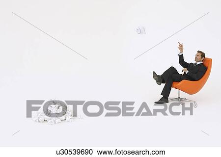 Stock Image - Businessman throwing piece of crumpled paper on pile. Fotosearch