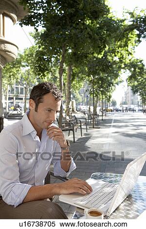 Businessman using laptop at outdoor cafe View Large Photo Image Stock Photography - Businessman using laptop at outdoor cafe. Fotosearch