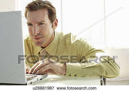 Stock Photo - Businessman using laptop in office. Fotosearch