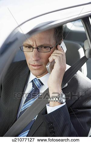 Stock Photo - Businessman using mobile phone in car elevated view. Fotosearch