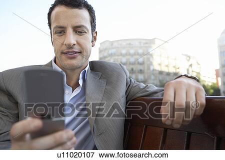 Businessman using mobile phone on city street View Large Photo Image Stock Photo - Businessman using mobile phone on city street. Fotosearch