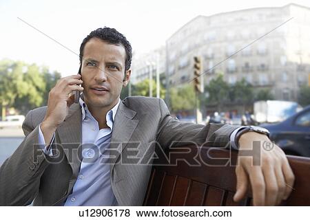 Stock Photo - Businessman using mobile phone on city street. Fotosearch