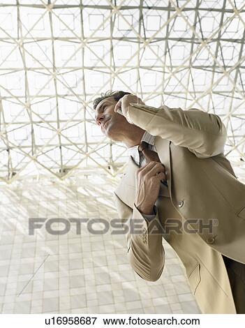 Stock Photo - Businessman using mobile phone outdoors (low angle view). Fotosearch