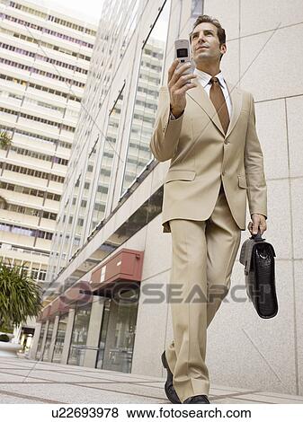 Stock Photo - Businessman using mobile phone outside office building. Fotosearch