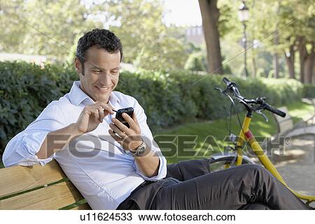 Businessman using palm pilot on park bench View Large Photo Image Stock Image - Businessman using palm pilot on park bench. Fotosearch