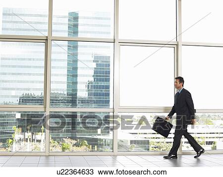 Businessman walking by office window View Large Photo Image Stock Image - Businessman walking by office window. Fotosearch