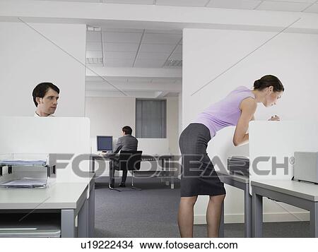 Picture - Businessman watching female colleague in office. Fotosearch