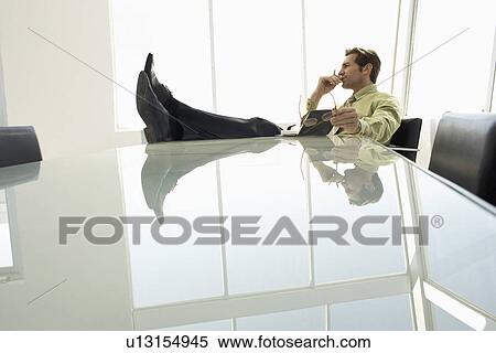 Businessman with feet up in conference room View Large Photo Image Stock Photography - Businessman with feet up in conference room. Fotosearch