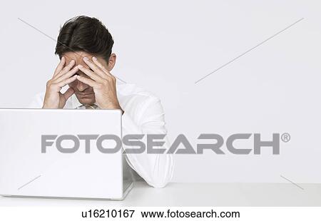 Businessman with head in hands in front of laptop View Large Photo Image Stock Photo - Businessman with head in hands in front of laptop. Fotosearch