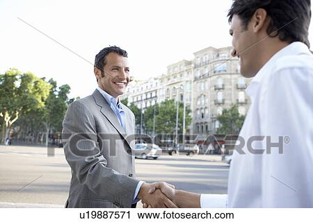 Businessmen shaking hands on city street by high-rise buildings View Large Photo Image Stock Image - Businessmen shaking hands on city street by high-rise buildings. Fotosearch