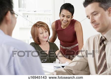 Businesspeople conferring around office desk View Large Photo Image Stock Image - Businesspeople conferring around office desk. Fotosearch