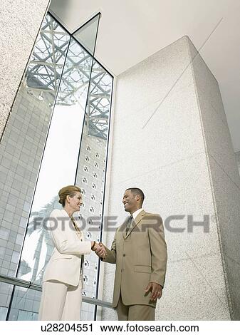 Businesspeople shaking hands in office building (low angle view) View Large Photo Image Stock Image - Businesspeople shaking hands in office building (low angle view). Fotosearch
