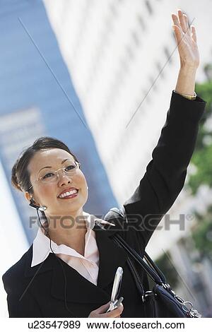 Businesswoman Hailing Cab using Cell Phone with hands free View Large Photo Image Stock Photo - Businesswoman Hailing Cab using Cell Phone with hands free. Fotosearch