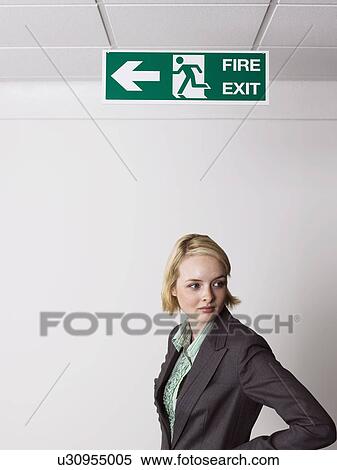 Businesswoman standing under exit sign View Large Photo Image Stock Photography - Businesswoman standing under exit sign. Fotosearch