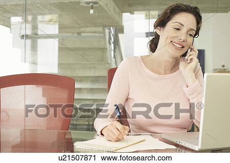 Stock Image - Businesswoman Using Cell Phone and Laptop. Fotosearch