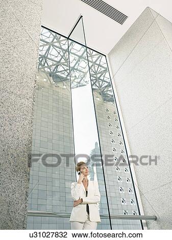 Businesswoman using mobile phone in office building (low angle view) View Large Photo Image Stock Image - Businesswoman using mobile phone in office building (low angle view). Fotosearch