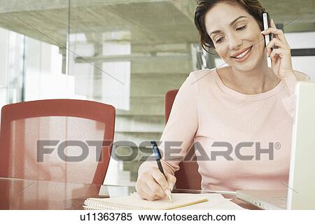 Stock Photography - Businesswoman using mobile phone in office. Fotosearch