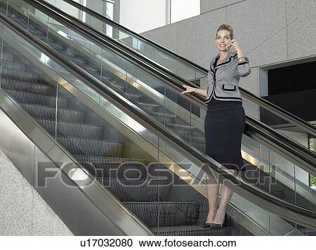 Businesswoman using mobile phone on escalator View Large Photo Image Stock Image - Businesswoman using mobile phone on escalator. Fotosearch