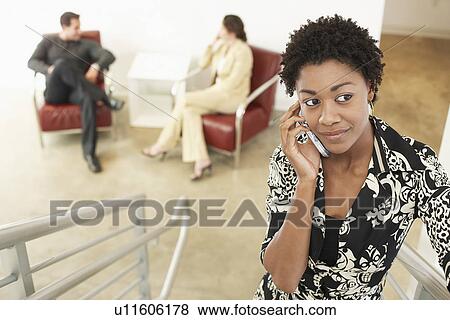 Stock Photo - Businesswoman using mobile phone on stairs. Fotosearch
