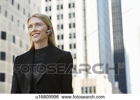 Businesswoman using wireless headset outdoors View Large Photo Image Stock Photograph - Businesswoman using wireless headset outdoors. Fotosearch