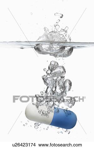 Picture - Capsule pill sinking in water close-up. Fotosearch