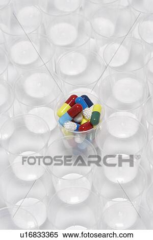 Stock Photography - Capsule pills in a plastic cup surrounded by empty plastic cups. Fotosearch