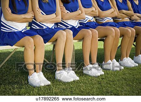 Stock Photography - Cheerleaders sitting on bench (low section). Fotosearch