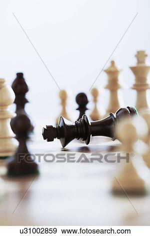 Chess game king lying on board surrounded by pieces View Large Photo Image Stock Photo - Chess game king lying on board surrounded by pieces. Fotosearch
