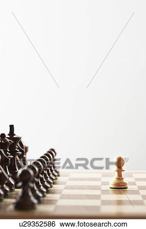 Stock Photograph - Chess game single white piece in front of black pieces. Fotosearch