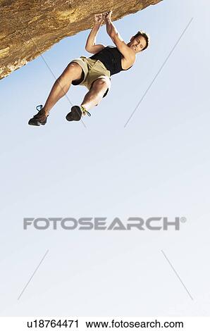 Stock Image - Climber Jumping off Cliff (low angle view). Fotosearch