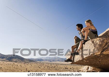 Stock Photo - Climbers sitting on Rock Looking at Desert. Fotosearch