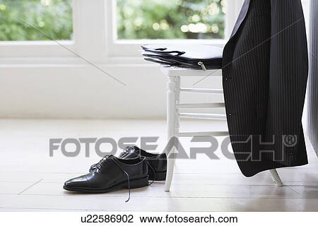 Stock Image - Clothing of businessman on chair and floor. Fotosearch